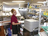 Foodservice staff prepares trays for meal delivery service.